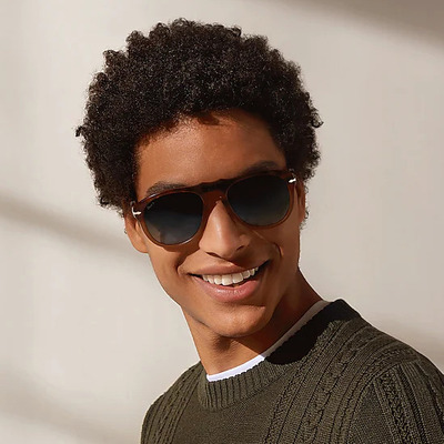 man curly hair wearing dark blue persol sunglasses