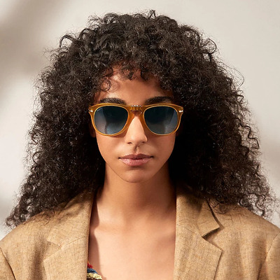 woman curly hair wearing gold persol sunglasses