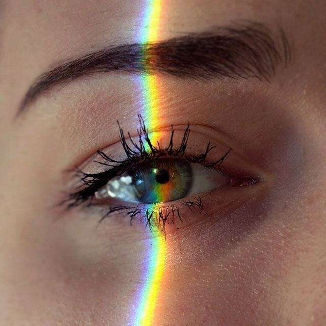 close up of an eye with slice of rainbow light over it