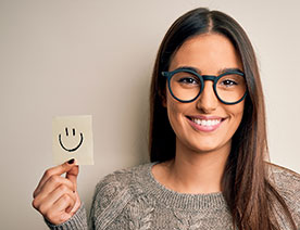 woman wearing glasses holding smiley