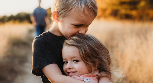 brother and sister hugging each other and smiling