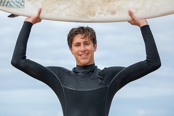 surefer in wetsuit holding board