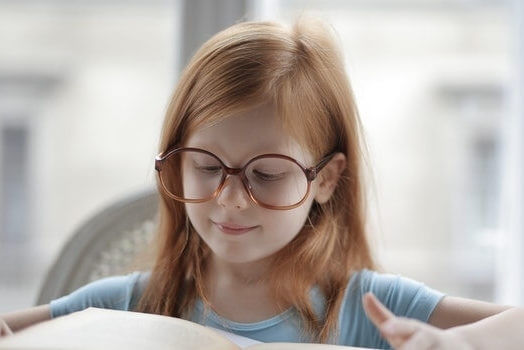 little girl wearing glasses reading a book 640×350