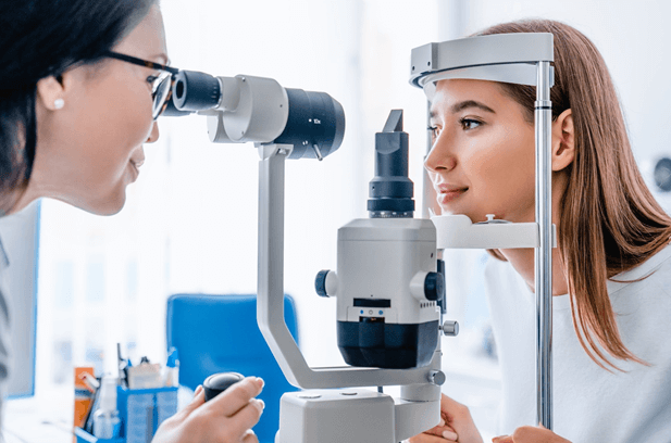 Side perspective of an eye doctor using a microscope and slit lamp to view a patients eye