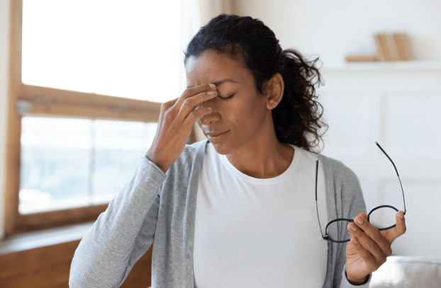 Woman taking off her glasses to rub her temples because of her dry eye symptoms