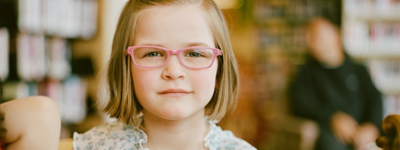 young girl pink eyeglasses in library