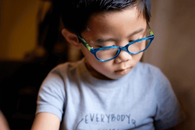young boy wearing glasses reading