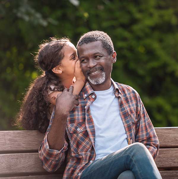older Black man with his daughter at the park smiling at eye clinic near you