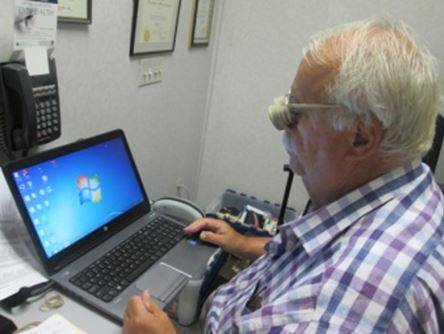 Man using computer with low vision assistance device