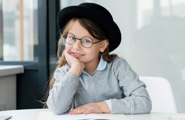 cute young girl eyeglasses reading at desk 640x416