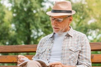 senior man reading park bench