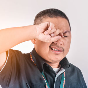 comprehensive eye exams asian man rubs eye
