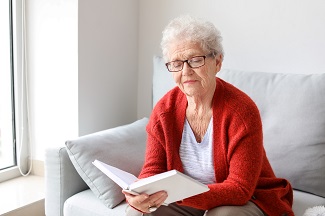 senior woman reading book sofa