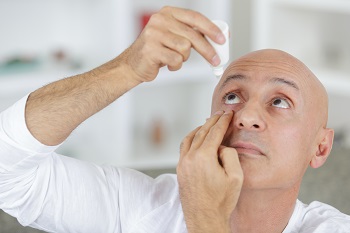 mature man using eye drops