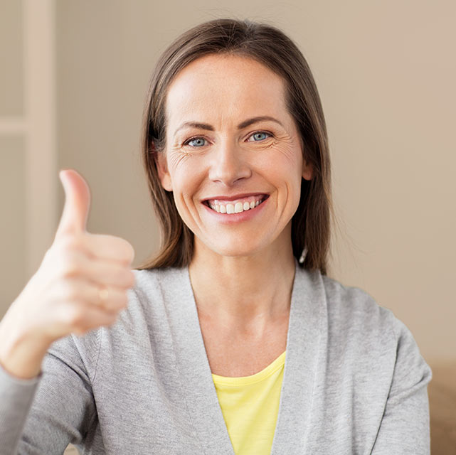 middle age woman with thumbs up warm background