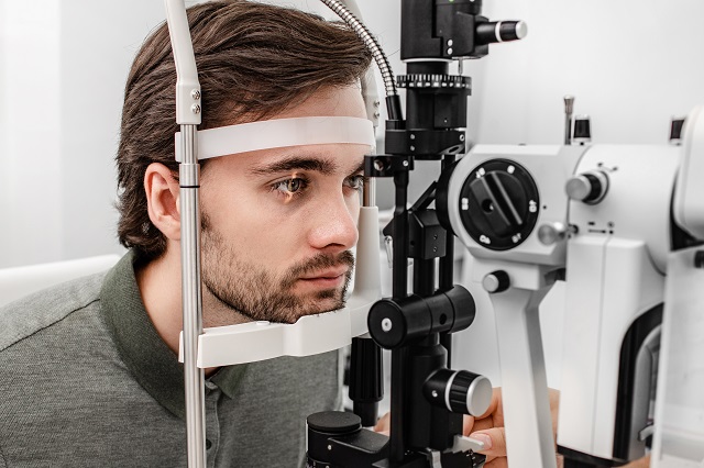 young professional man behind slit lamp