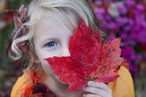 girl with autumn red maple leaf over eye