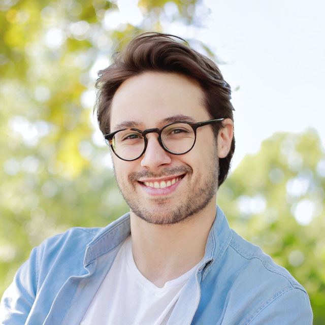Smiling man wearing glasses and a denim shirt
