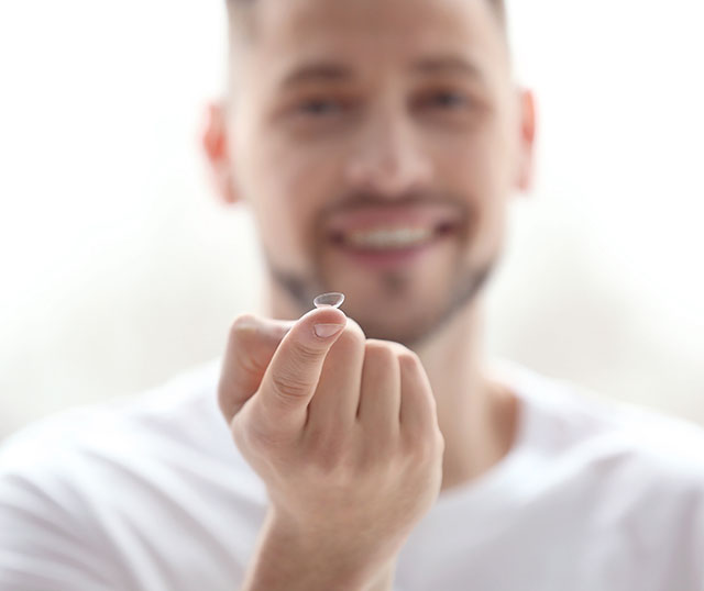 Guy holding contact lens on finger