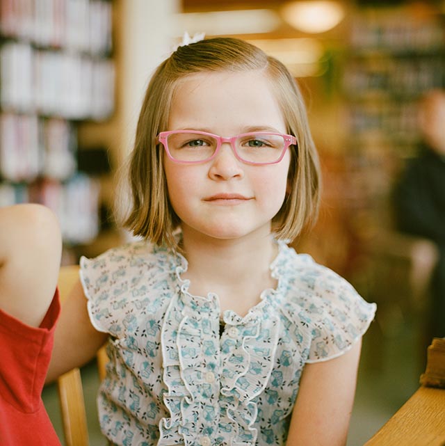 young girl modeling pink eyeglasses