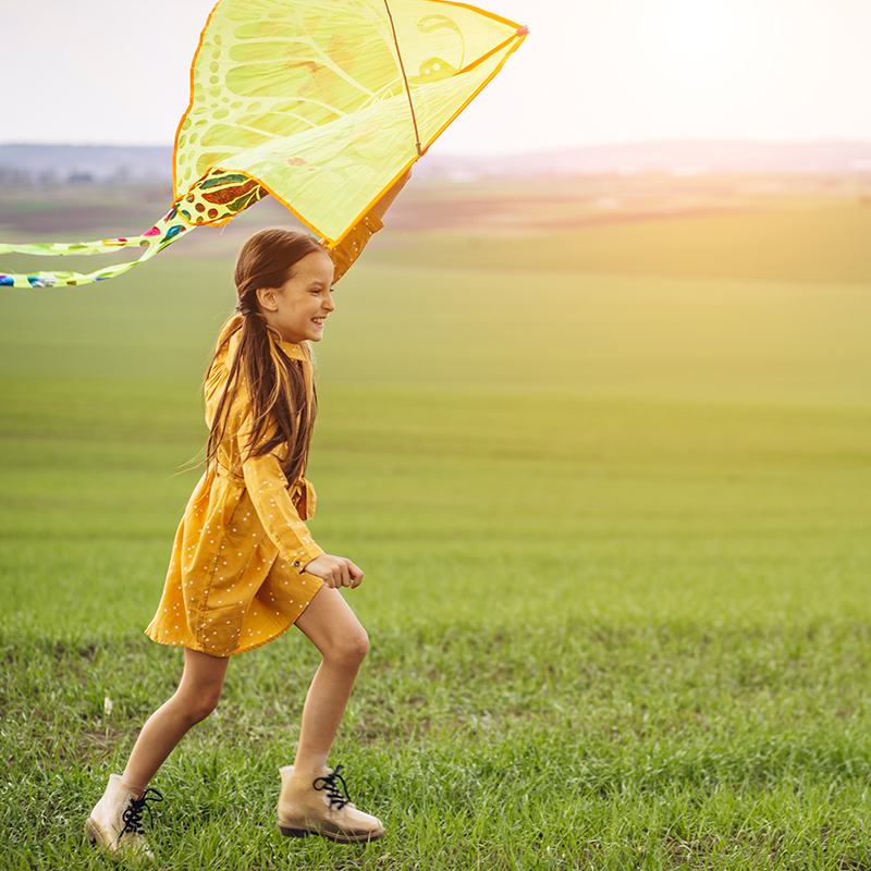 young girl playing with a kite in the field