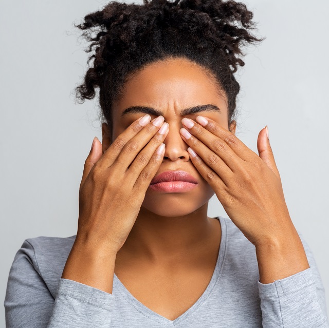 Woman covering sore eyes with hands