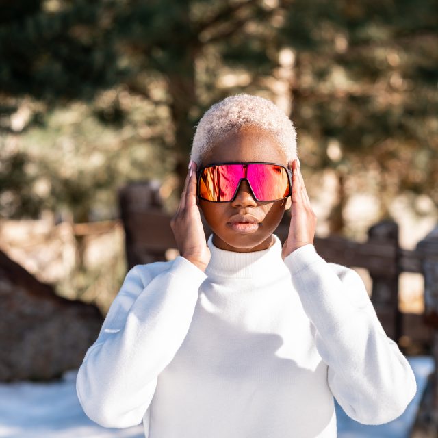 African American woman standing with sunglasses in a snowy park