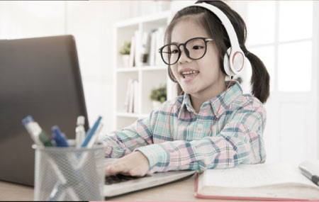 Child wearing eyeglass using laptop