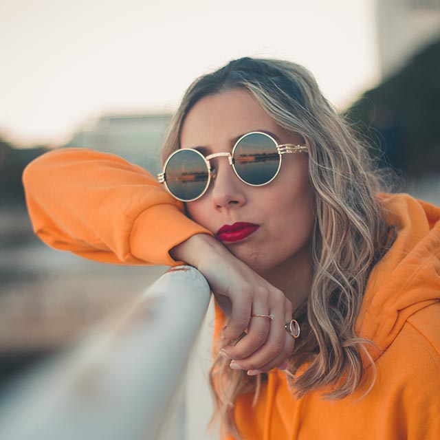 woman modeling sunglasses and orange jacket
