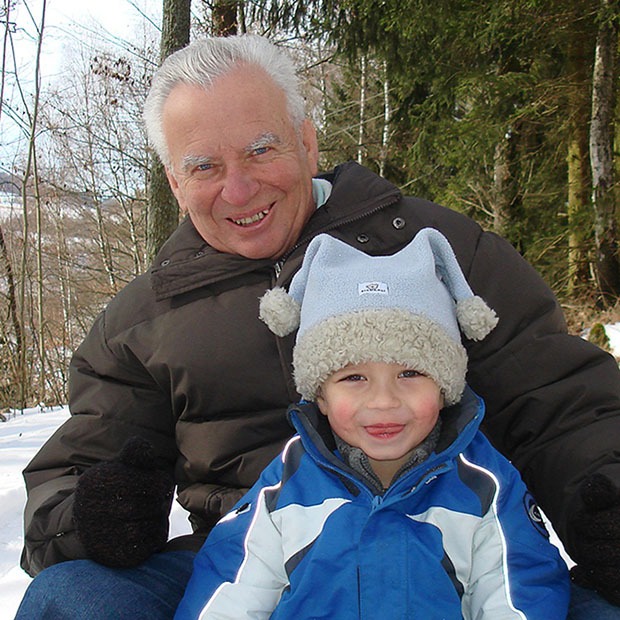 Older man and grandchild posing outside in the snow