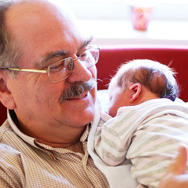 Older man with glasses holding a baby