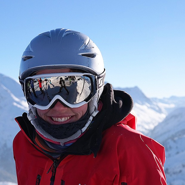Adult smiling in snow gear, in the snow capped mountains