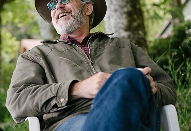 Older man sitting outdoors laughing with sunglasses