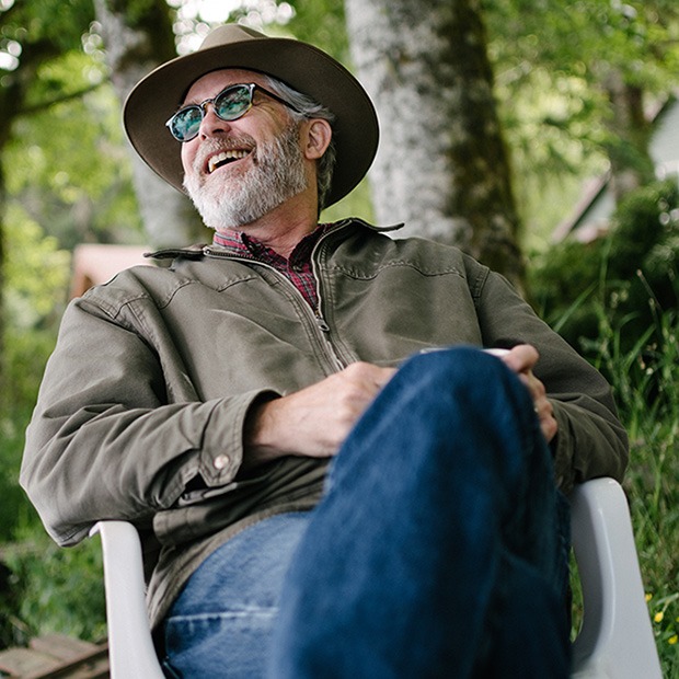 Older man sitting outdoors laughing with sunglasses