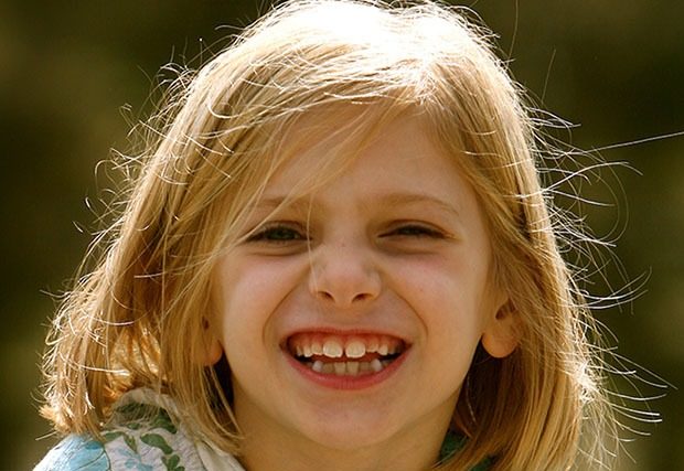 Young girl smiling happily at camera outside