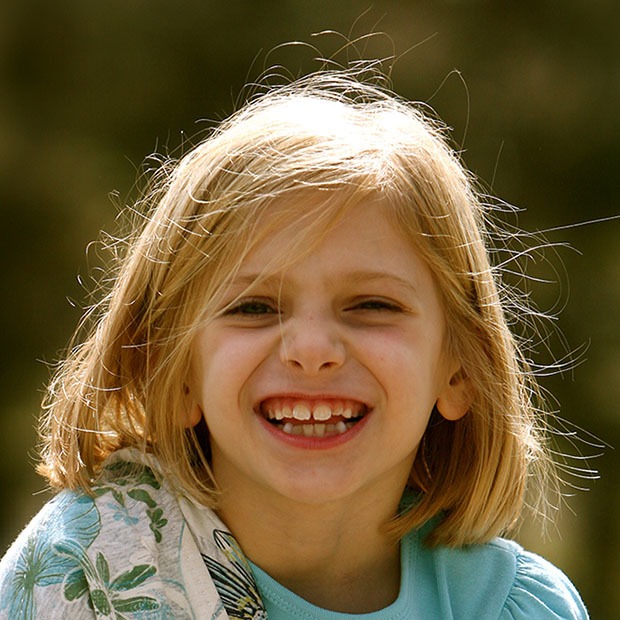 Young girl smiling happily at camera outside