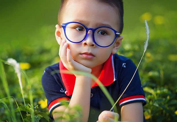 young boy with blue circular frames outside