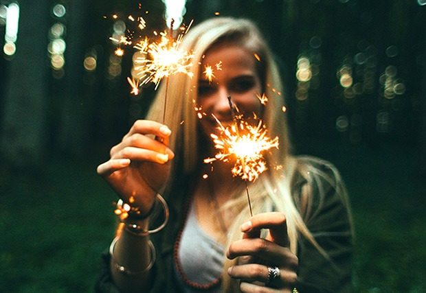 Young woman holding out lit sparklers
