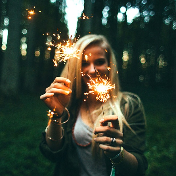 Young woman holding out lit sparklers