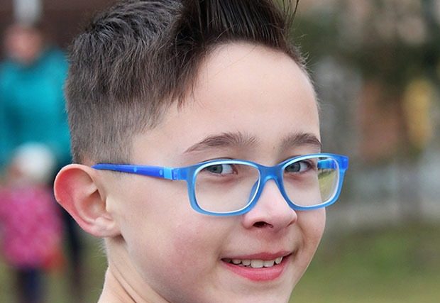Young boy with blue glasses smiling