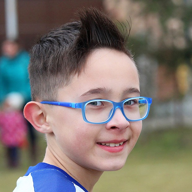 Young boy with blue glasses smiling