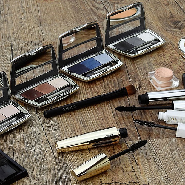 Various makeup kits, eyeshadow, mascara, displayed on a wooden table