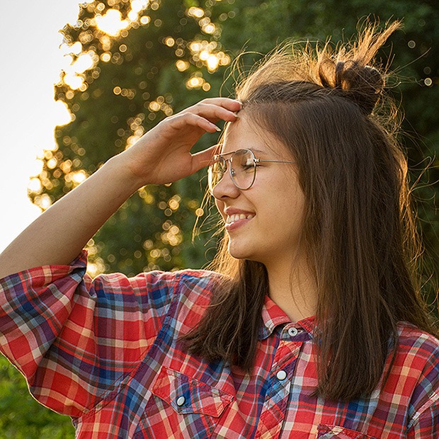 Young teenage girl smiling with glasses, getting face out of the way of her face