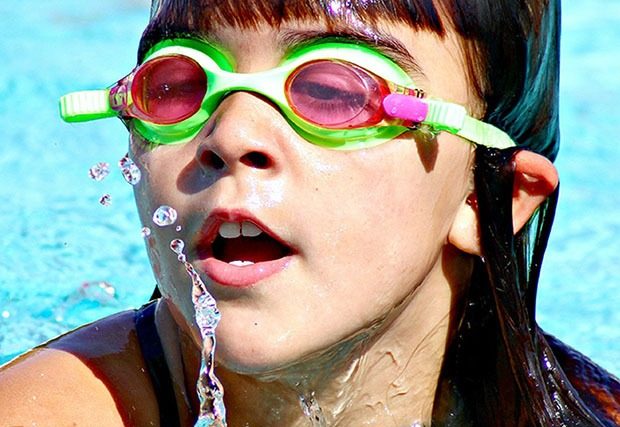 Young girl swimming with green goggles on