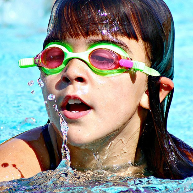 Young girl swimming with green goggles on