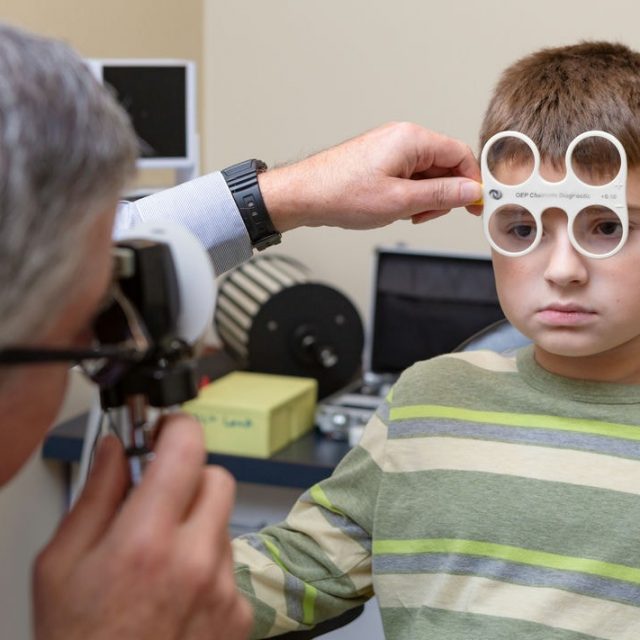 male optometrist performing eye examination on young patient