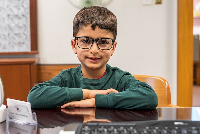 young boy wearing glasses at desk