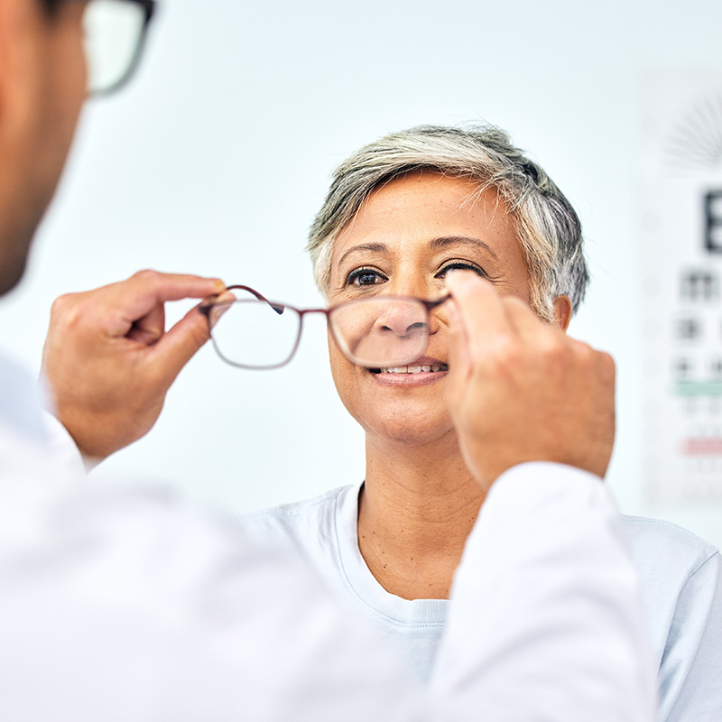 Doctor fitting eyeglasses on patient