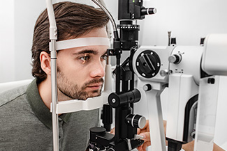 Adult man getting an eye exam at ophthalmology clinic. Checking retina of a male eye close up