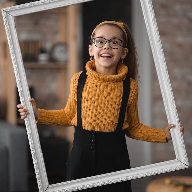 smiling girl in glasses wearing yellow sweater